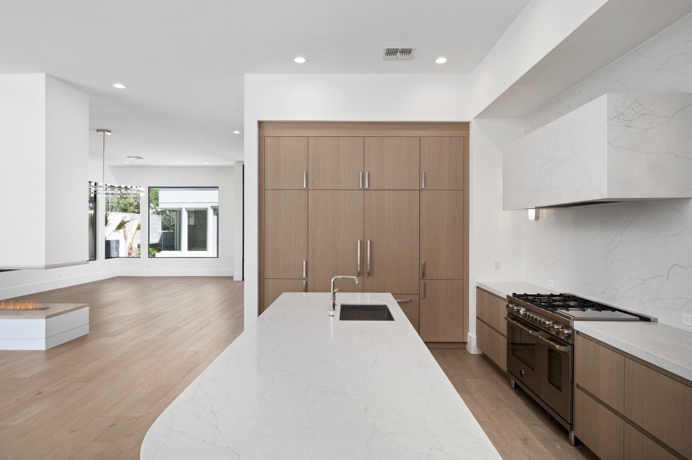 Cette photo montre une grande cuisine moderne en L et bois brun avec un placard à porte plane, un plan de travail en quartz modifié, une crédence en quartz modifié et un sol en bois brun.