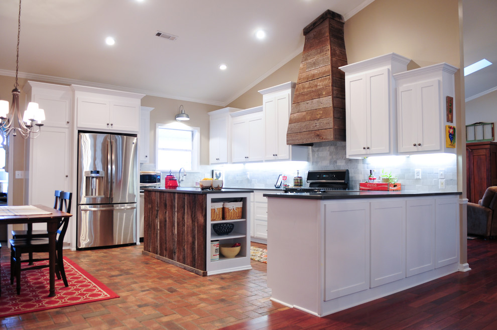 Foto på ett mellanstort rustikt kök, med en dubbel diskho, skåp i shakerstil, vita skåp, bänkskiva i kvartsit, vitt stänkskydd, stänkskydd i tunnelbanekakel, rostfria vitvaror, tegelgolv och flera köksöar