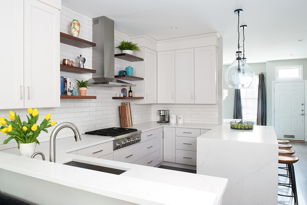 Bild på ett mellanstort funkis vit vitt kök, med en undermonterad diskho, luckor med infälld panel, vita skåp, bänkskiva i kvarts, vitt stänkskydd, stänkskydd i keramik, rostfria vitvaror, mörkt trägolv, en halv köksö och grått golv