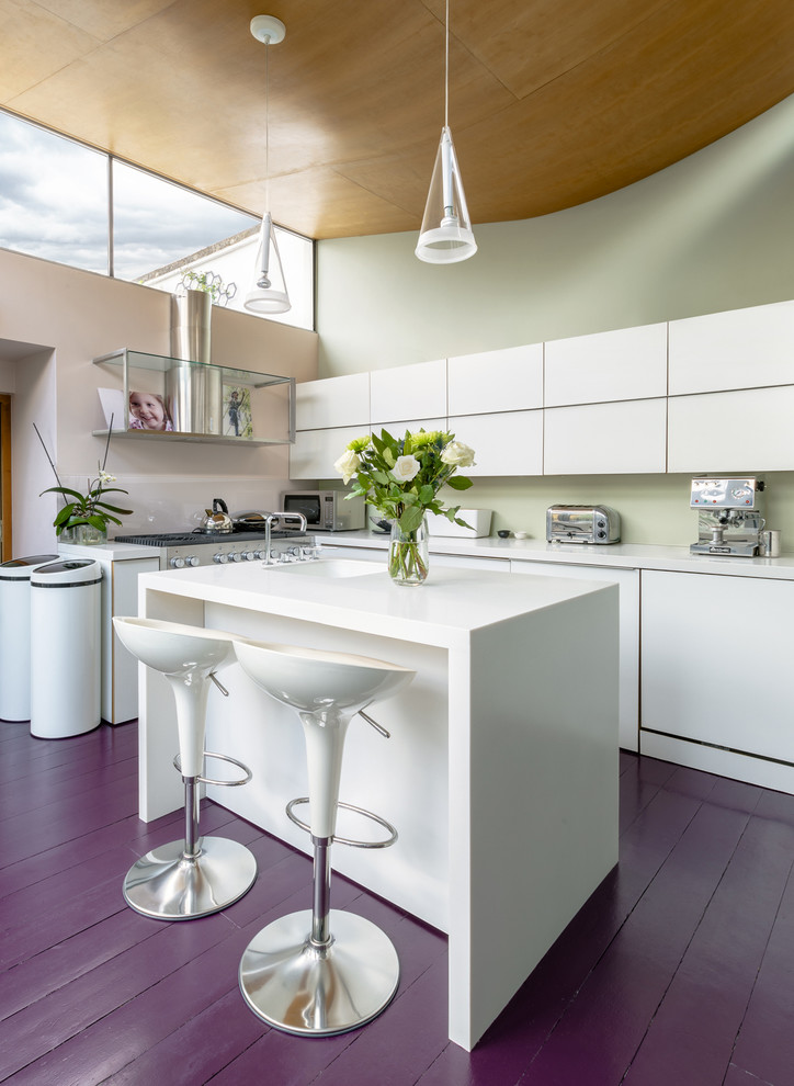 Medium sized contemporary l-shaped open plan kitchen in London with an integrated sink, flat-panel cabinets, white cabinets, quartz worktops, glass sheet splashback, stainless steel appliances, an island, painted wood flooring and purple floors.