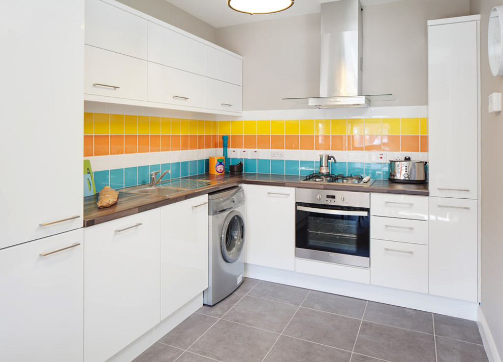 На фото: кухня со стиральной машиной в современном стиле с техникой из нержавеющей стали и разноцветным фартуком