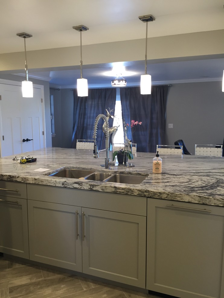 Large trendy u-shaped limestone floor eat-in kitchen photo in Denver with a triple-bowl sink, shaker cabinets, white cabinets, granite countertops, gray backsplash, stone tile backsplash, stainless steel appliances and an island