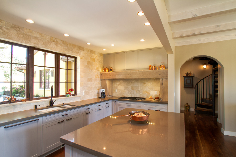 Inspiration for a mediterranean u-shaped medium tone wood floor open concept kitchen remodel in Portland with an undermount sink, beige backsplash, an island, shaker cabinets, white cabinets, quartzite countertops, stone tile backsplash and paneled appliances