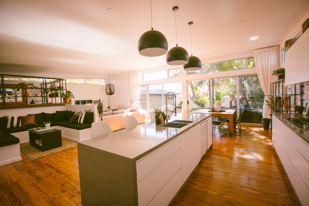 Offene, Einzeilige, Mittelgroße Moderne Küche mit Unterbauwaschbecken, flächenbündigen Schrankfronten, weißen Schränken, Küchenrückwand in Weiß, Rückwand aus Metrofliesen, braunem Holzboden und Kücheninsel in Sydney