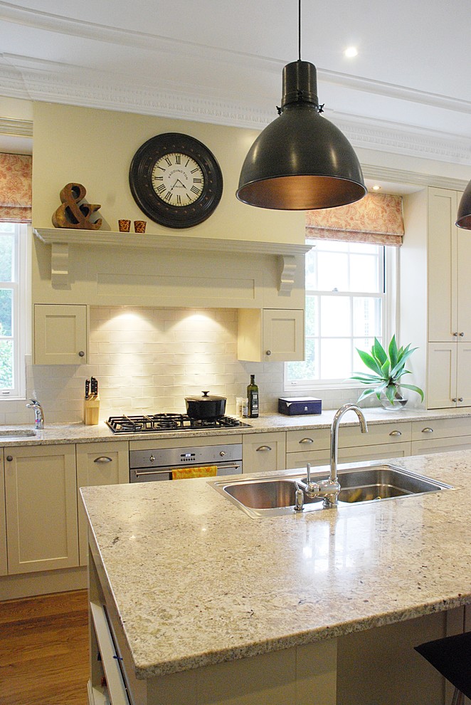 Bild på ett stort vintage kök och matrum, med en dubbel diskho, skåp i shakerstil, vita skåp, granitbänkskiva, vitt stänkskydd, stänkskydd i tunnelbanekakel, rostfria vitvaror och en köksö