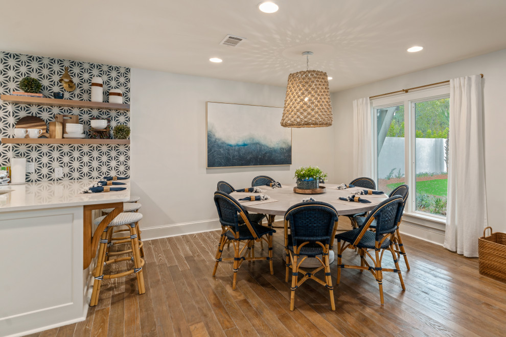 Idée de décoration pour une salle à manger marine de taille moyenne avec un mur blanc, un sol en bois brun, une cheminée double-face, un manteau de cheminée en plâtre et un sol gris.
