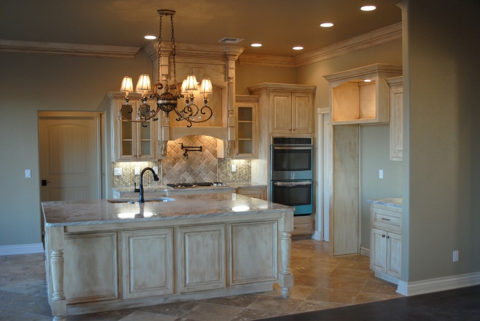 Example of a mid-sized classic travertine floor eat-in kitchen design in Oklahoma City with an undermount sink, raised-panel cabinets, distressed cabinets, granite countertops, gray backsplash, mosaic tile backsplash, stainless steel appliances and an island
