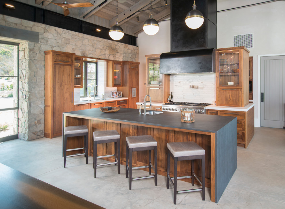 サンフランシスコにあるラスティックスタイルのおしゃれなアイランドキッチン (シングルシンク、中間色木目調キャビネット、白いキッチンパネル、大理石のキッチンパネル、シルバーの調理設備、グレーの床) の写真