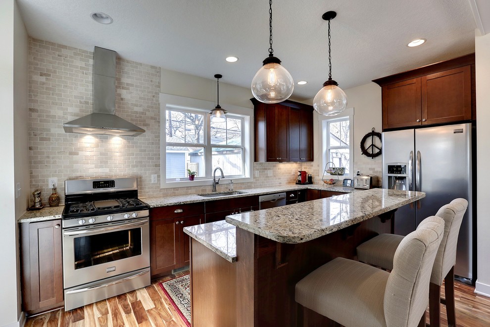 Design ideas for a traditional l-shaped kitchen in Minneapolis with a submerged sink, recessed-panel cabinets, dark wood cabinets, grey splashback and stainless steel appliances.
