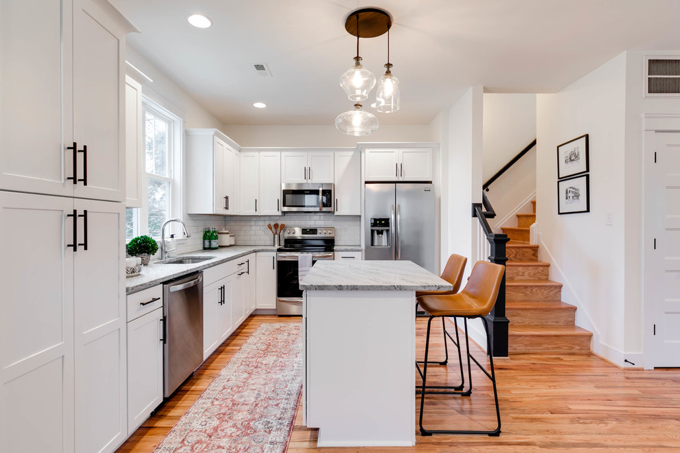 Inspiration for a mid-sized scandinavian l-shaped light wood floor eat-in kitchen remodel in Richmond with an undermount sink, recessed-panel cabinets, white cabinets, granite countertops, white backsplash, ceramic backsplash, stainless steel appliances and an island