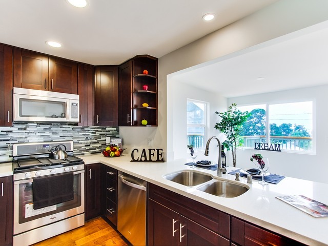 Exempel på ett litet exotiskt vit vitt kök, med en dubbel diskho, skåp i shakerstil, skåp i mörkt trä, bänkskiva i kvarts, flerfärgad stänkskydd, stänkskydd i stickkakel, rostfria vitvaror, mellanmörkt trägolv, en halv köksö och brunt golv