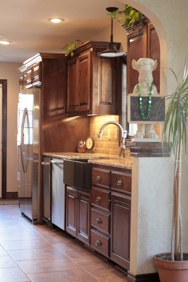 Exempel på ett mellanstort klassiskt kök, med en rustik diskho, luckor med upphöjd panel, skåp i mellenmörkt trä, granitbänkskiva, beige stänkskydd, stänkskydd i stenkakel, rostfria vitvaror och klinkergolv i keramik