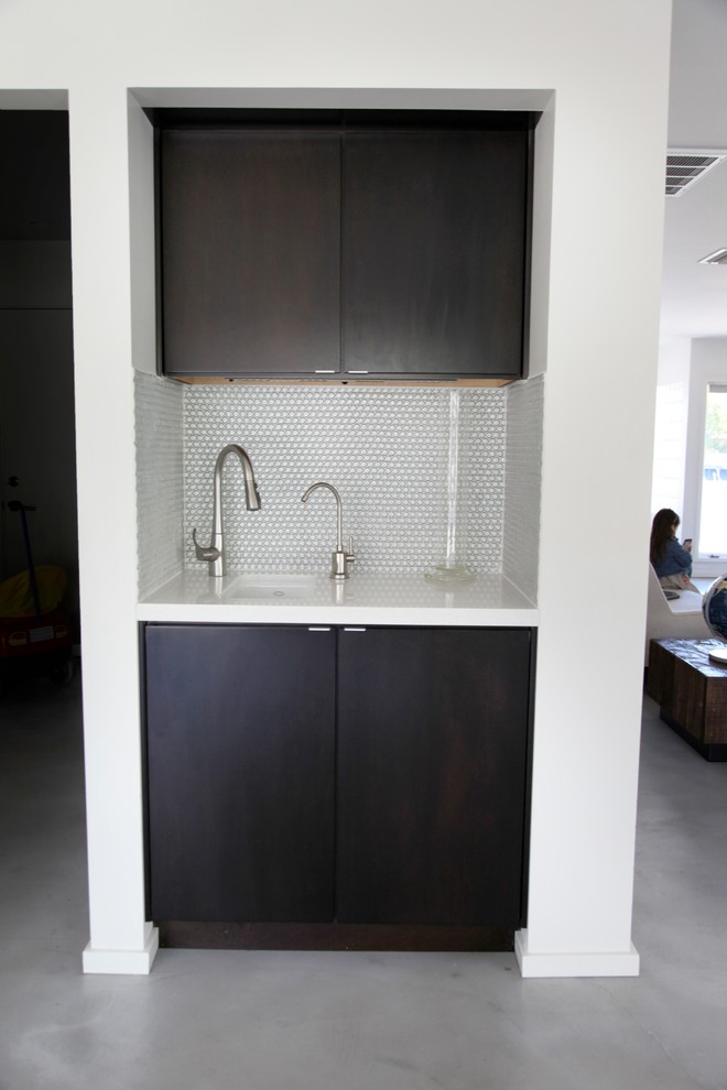 Medium sized contemporary l-shaped enclosed kitchen in Phoenix with a submerged sink, flat-panel cabinets, dark wood cabinets, composite countertops, white splashback, mosaic tiled splashback, stainless steel appliances, concrete flooring and an island.