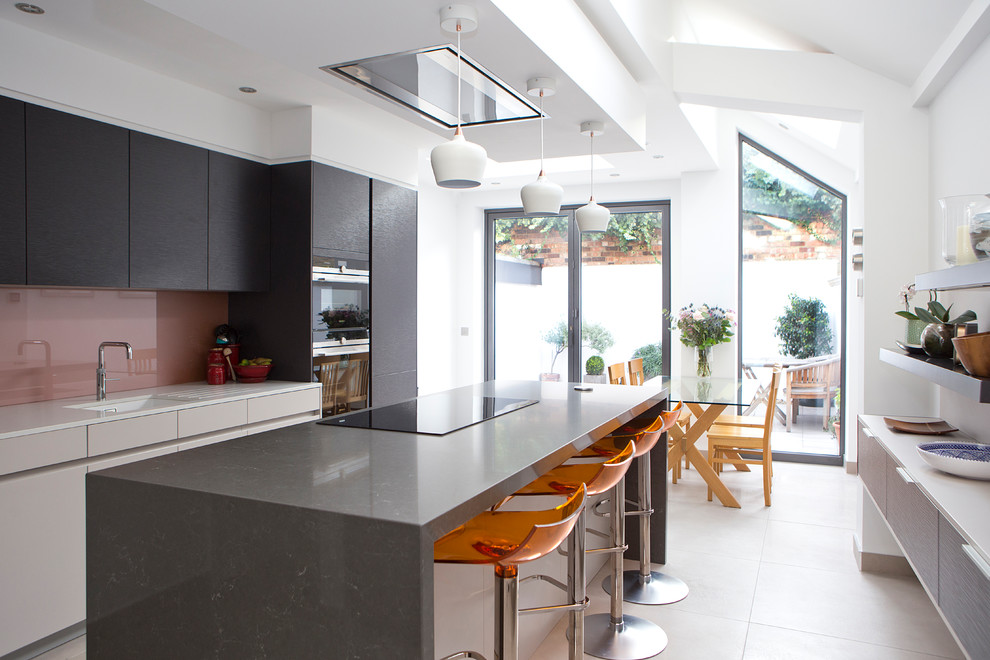 Immagine di una cucina minimal di medie dimensioni con ante lisce, lavello sottopiano, ante nere, paraspruzzi rosso, paraspruzzi con lastra di vetro, elettrodomestici da incasso e pavimento beige