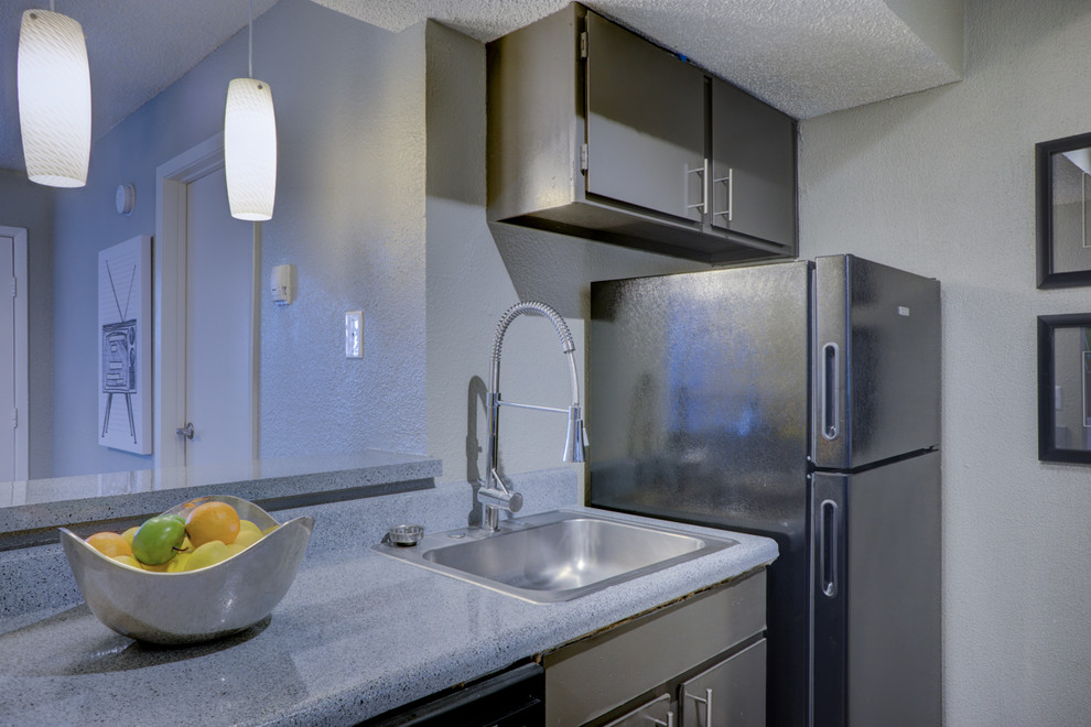 Exempel på ett litet modernt kök, med en nedsänkt diskho, släta luckor, grå skåp, laminatbänkskiva, stänkskydd med metallisk yta, stänkskydd i glaskakel, svarta vitvaror och mörkt trägolv
