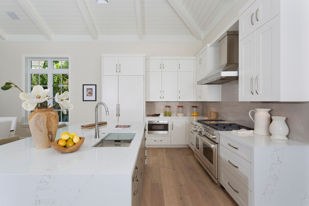 Idéer för att renovera ett stort tropiskt vit vitt kök, med en dubbel diskho, luckor med infälld panel, vita skåp, marmorbänkskiva, beige stänkskydd, stänkskydd i keramik, rostfria vitvaror, mellanmörkt trägolv, en köksö och brunt golv