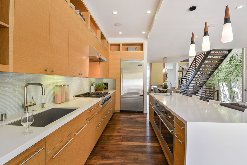 Inspiration for a contemporary medium tone wood floor open concept kitchen remodel in San Francisco with an undermount sink, flat-panel cabinets, light wood cabinets, green backsplash, stainless steel appliances and an island