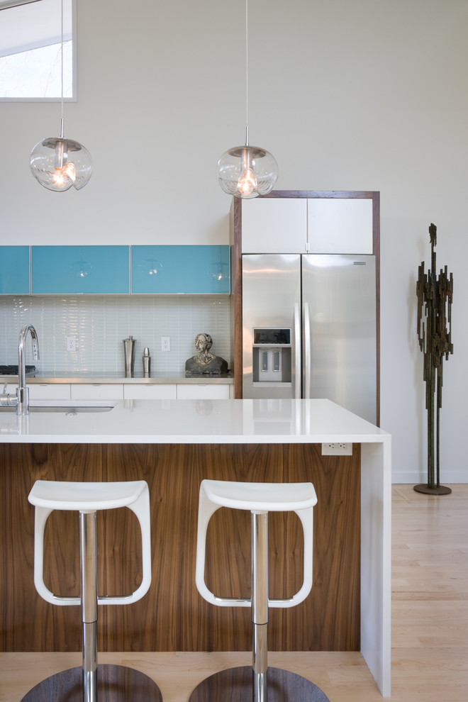 Cette photo montre une cuisine tendance avec une crédence en carreau de verre, un électroménager en acier inoxydable, une crédence blanche et un placard à porte plane.