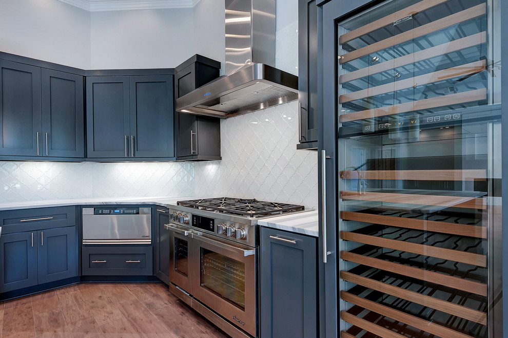 Example of a trendy kitchen design in Miami with gray cabinets, glass countertops, white backsplash and an island
