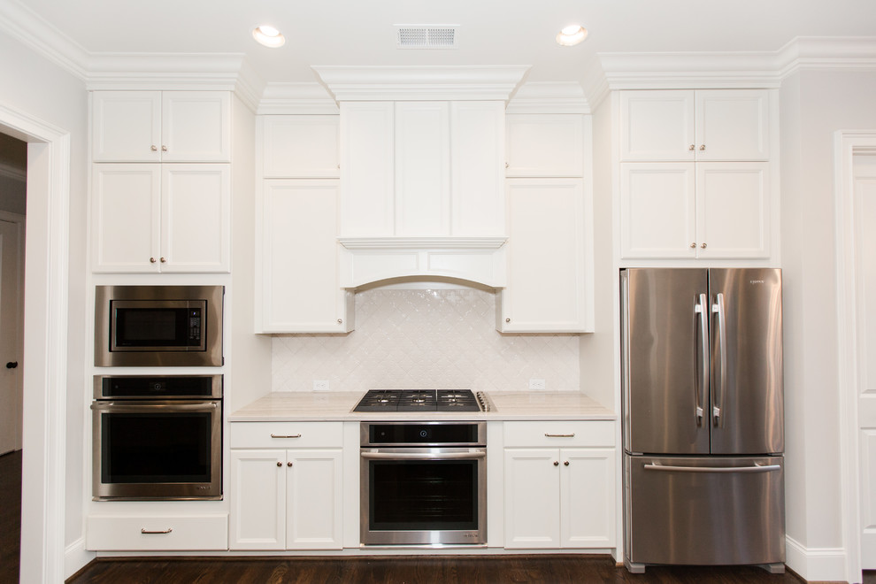 Bild på ett stort funkis vit vitt kök, med en rustik diskho, luckor med infälld panel, vita skåp, bänkskiva i kvartsit, vitt stänkskydd, stänkskydd i keramik, rostfria vitvaror, mörkt trägolv, en köksö och brunt golv