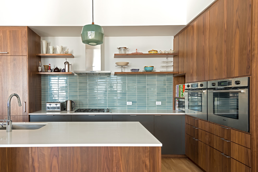 Moderne Küche mit Unterbauwaschbecken, flächenbündigen Schrankfronten, hellbraunen Holzschränken, Küchenrückwand in Blau, Küchengeräten aus Edelstahl, braunem Holzboden und Kücheninsel in New York