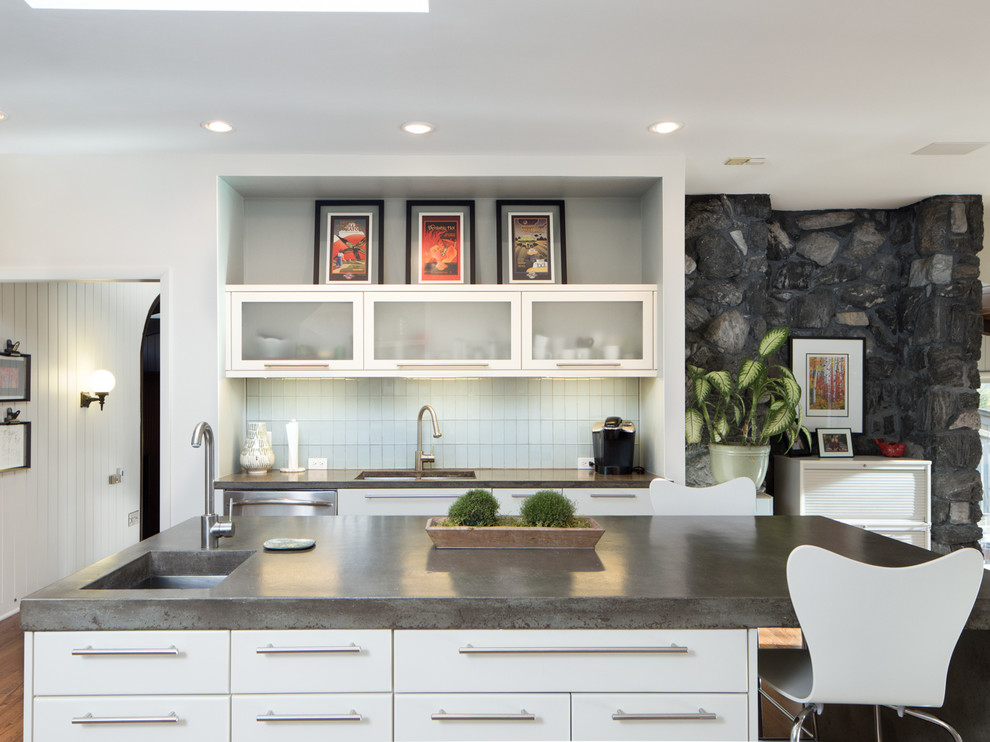 Exempel på ett stort retro kök, med en undermonterad diskho, släta luckor, vita skåp, bänkskiva i betong, blått stänkskydd, stänkskydd i glaskakel, rostfria vitvaror, mellanmörkt trägolv och en köksö