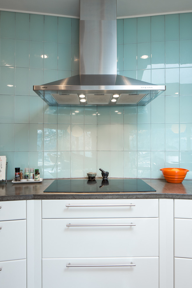 Immagine di una grande cucina minimalista con lavello sottopiano, ante lisce, ante bianche, top in cemento, paraspruzzi blu, paraspruzzi con piastrelle di vetro, elettrodomestici in acciaio inossidabile e pavimento in legno massello medio