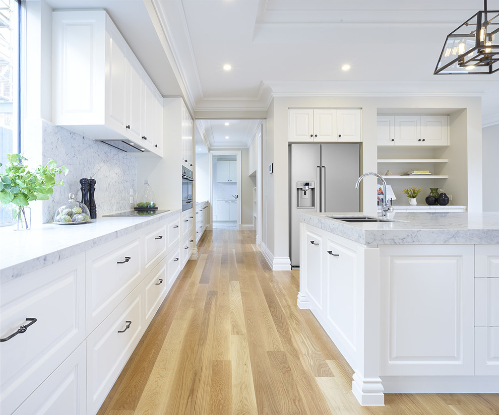 Inspiration for a large timeless single-wall light wood floor kitchen pantry remodel in Melbourne with a double-bowl sink, quartz countertops, white backsplash, stone tile backsplash, white appliances, an island and raised-panel cabinets