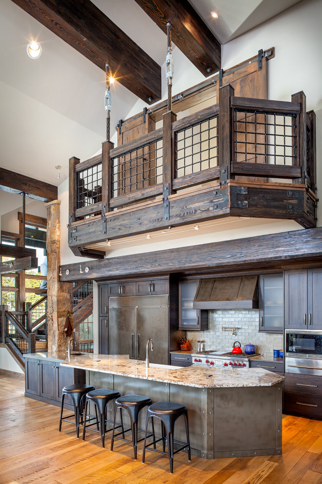 Mountain style galley medium tone wood floor open concept kitchen photo in Denver with shaker cabinets, dark wood cabinets and an island
