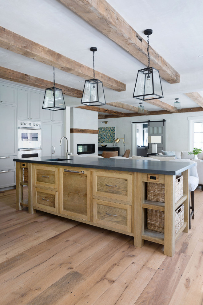 Idée de décoration pour une grande cuisine ouverte encastrable champêtre en L et bois brun avec un sol en bois brun, îlot, un évier intégré, un placard à porte shaker, un sol beige, un plan de travail gris et poutres apparentes.