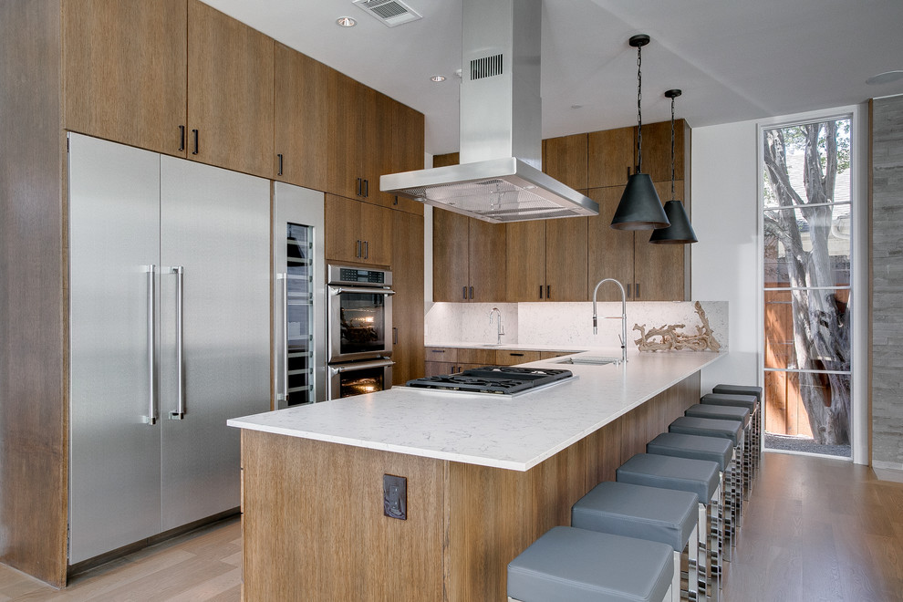 Moderne Küche mit Unterbauwaschbecken, flächenbündigen Schrankfronten, hellbraunen Holzschränken, Küchenrückwand in Weiß, Küchengeräten aus Edelstahl, braunem Holzboden und Kücheninsel in Dallas
