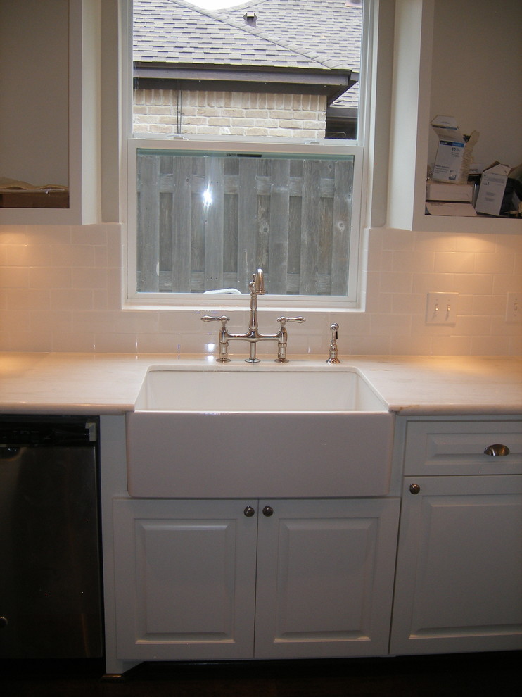 This is an example of a small traditional u-shaped enclosed kitchen in Houston with a belfast sink, raised-panel cabinets, white cabinets, granite worktops, white splashback, ceramic splashback, stainless steel appliances, dark hardwood flooring and no island.