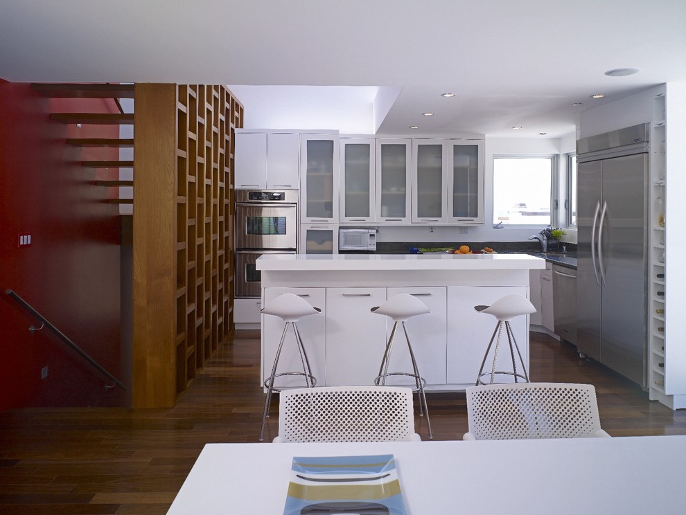 Example of a minimalist kitchen design in Los Angeles with glass-front cabinets and stainless steel appliances