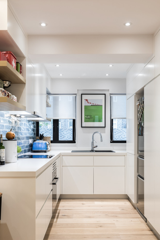 Inspiration for a contemporary u-shaped light wood floor and beige floor enclosed kitchen remodel in Hong Kong with a drop-in sink, flat-panel cabinets, white cabinets, blue backsplash, subway tile backsplash, black appliances and no island