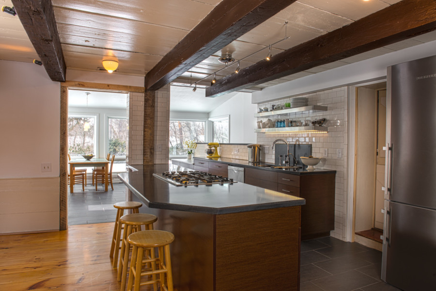 Large transitional galley porcelain tile eat-in kitchen photo in Boston with an undermount sink, flat-panel cabinets, dark wood cabinets, concrete countertops, white backsplash, subway tile backsplash, stainless steel appliances and an island
