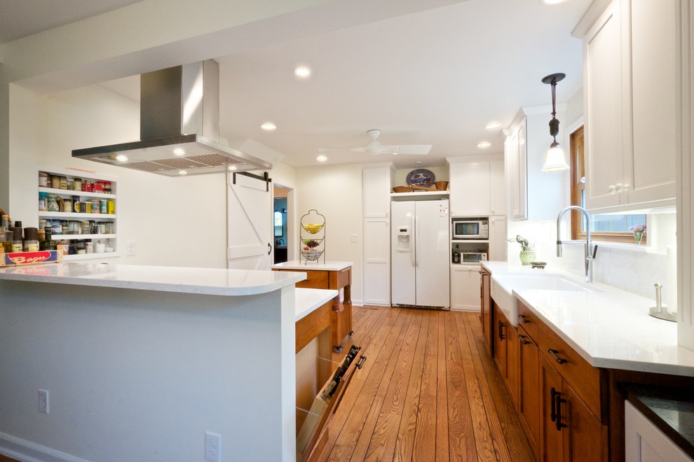 Foto på ett mellanstort lantligt vit u-kök, med en rustik diskho, luckor med infälld panel, skåp i mellenmörkt trä, bänkskiva i kvartsit, vitt stänkskydd, stänkskydd i sten, mellanmörkt trägolv, en köksö och brunt golv