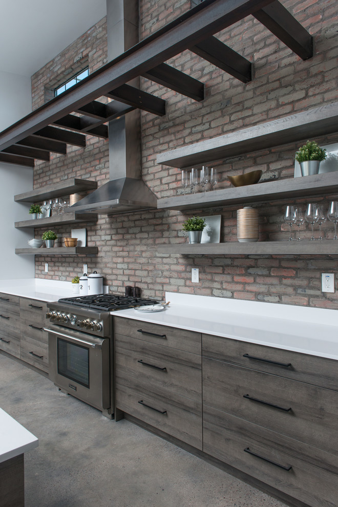 Example of a mid-sized urban l-shaped concrete floor and gray floor open concept kitchen design in Phoenix with an undermount sink, flat-panel cabinets, medium tone wood cabinets, quartzite countertops, red backsplash, brick backsplash, stainless steel appliances, an island and white countertops
