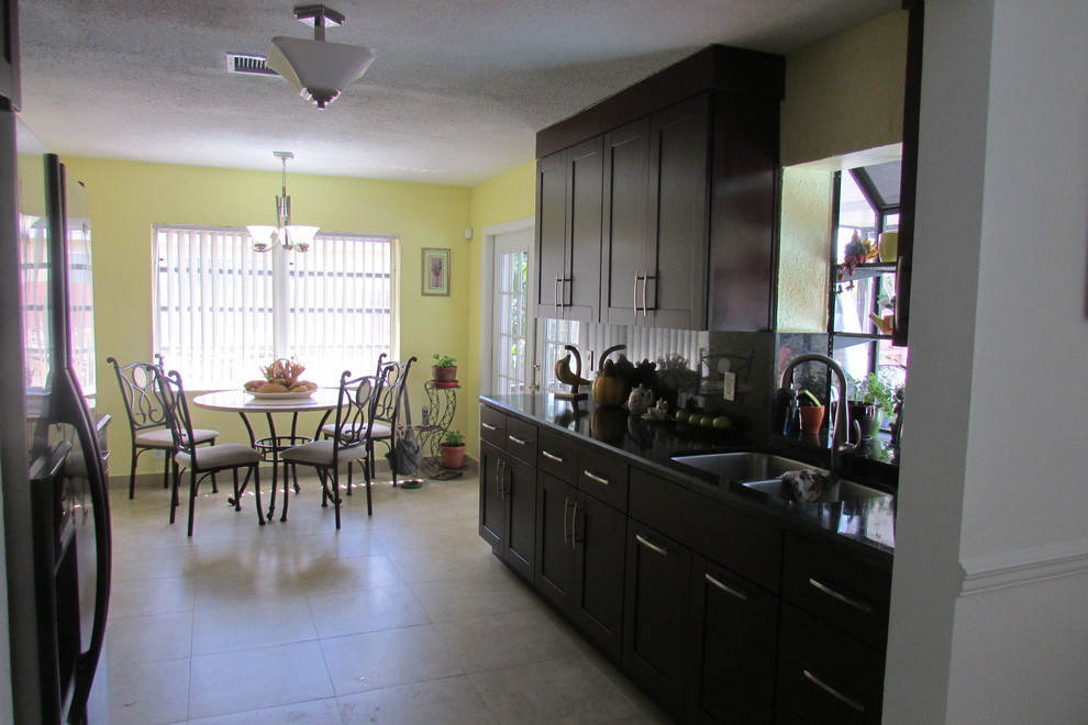 Zweizeilige, Mittelgroße Klassische Wohnküche mit Doppelwaschbecken, Schrankfronten im Shaker-Stil, dunklen Holzschränken, Granit-Arbeitsplatte, Küchenrückwand in Metallic, Küchengeräten aus Edelstahl und Terrakottaboden in Miami