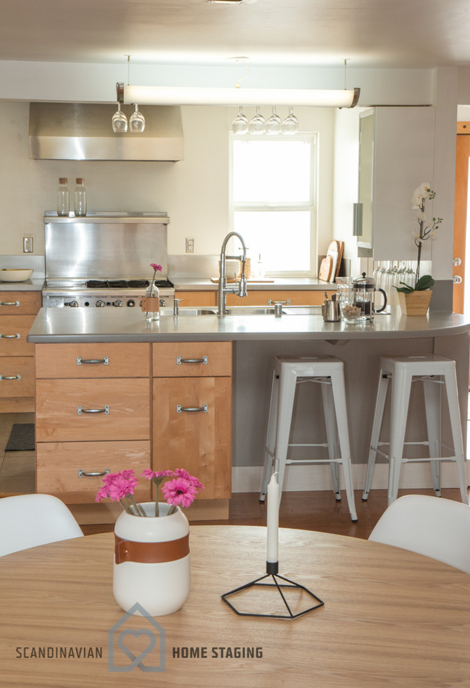 サンフランシスコにある北欧スタイルのおしゃれなアイランドキッチン (中間色木目調キャビネット、メタリックのキッチンパネル、メタルタイルのキッチンパネル、シルバーの調理設備、無垢フローリング) の写真