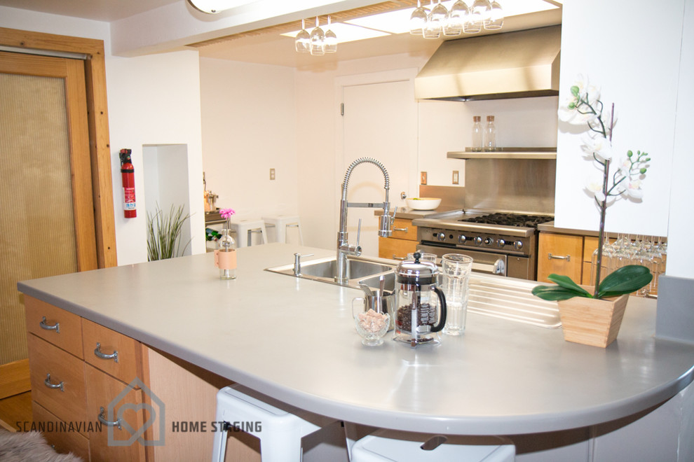 サンフランシスコにある北欧スタイルのおしゃれなアイランドキッチン (中間色木目調キャビネット、メタリックのキッチンパネル、メタルタイルのキッチンパネル、シルバーの調理設備、無垢フローリング) の写真