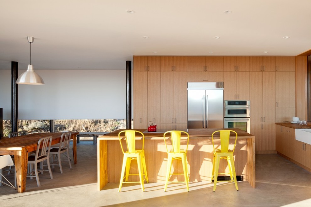 Идея дизайна: кухня в современном стиле с обеденным столом, с полувстраиваемой мойкой (с передним бортиком), плоскими фасадами, светлыми деревянными фасадами, деревянной столешницей, техникой из нержавеющей стали и островом