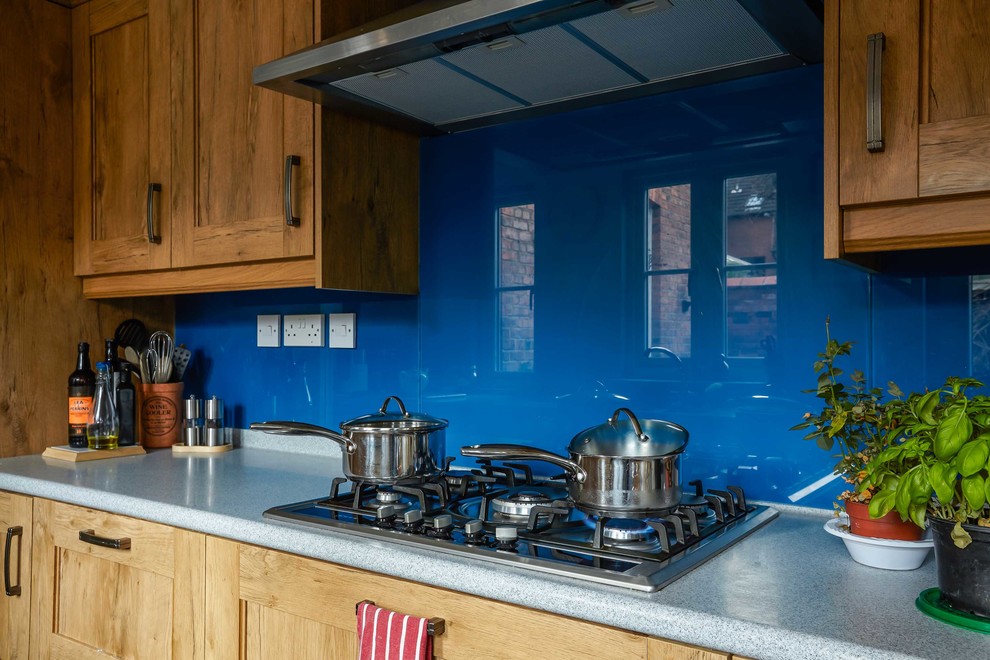 Idee per una cucina vittoriana chiusa con ante in legno scuro, paraspruzzi blu, paraspruzzi con lastra di vetro e elettrodomestici in acciaio inossidabile