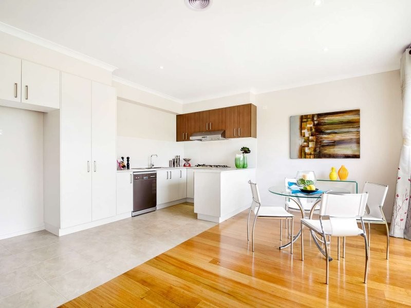 Photo of a small contemporary u-shaped enclosed kitchen in Melbourne with a built-in sink, flat-panel cabinets, white cabinets, engineered stone countertops, white splashback, ceramic splashback, stainless steel appliances, vinyl flooring, no island and brown floors.
