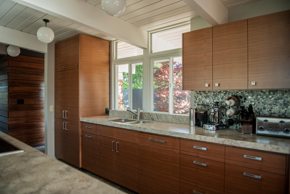 Example of a mid-sized trendy single-wall eat-in kitchen design in San Francisco with a double-bowl sink, flat-panel cabinets, medium tone wood cabinets, granite countertops, beige backsplash, stone tile backsplash, stainless steel appliances and an island
