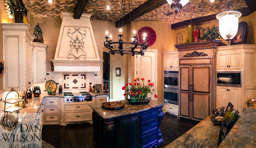 Open concept kitchen - large traditional u-shaped dark wood floor open concept kitchen idea in Austin with an undermount sink, raised-panel cabinets, distressed cabinets, granite countertops, beige backsplash, stone tile backsplash, stainless steel appliances and an island