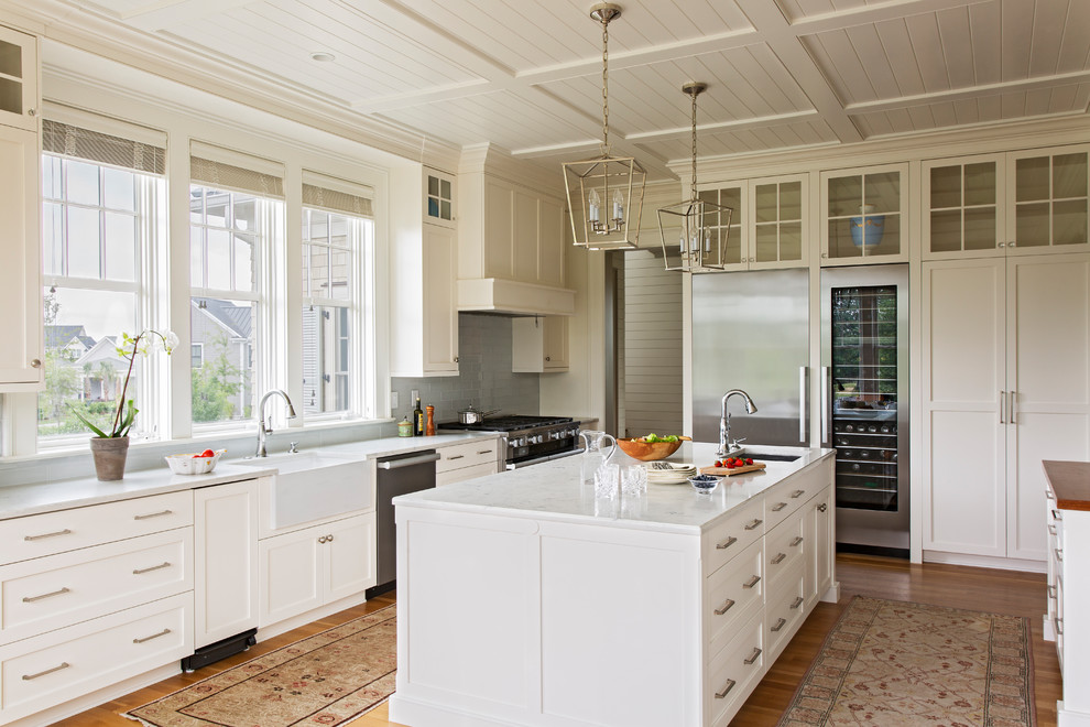 Exempel på ett maritimt vit vitt kök, med en undermonterad diskho, skåp i shakerstil, vita skåp, marmorbänkskiva, rostfria vitvaror, mellanmörkt trägolv, grått stänkskydd och flera köksöar