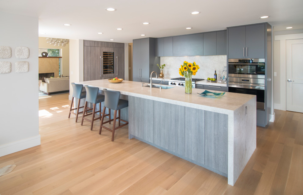 Zweizeilige Moderne Küche mit flächenbündigen Schrankfronten, Unterbauwaschbecken, grauen Schränken, Küchengeräten aus Edelstahl, braunem Holzboden, Kücheninsel, braunem Boden und weißer Arbeitsplatte in San Francisco