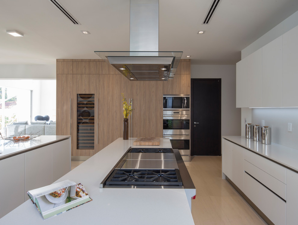 Medium sized contemporary kitchen in Miami with a built-in sink, flat-panel cabinets, white cabinets, wood worktops, white splashback, stainless steel appliances, porcelain flooring, multiple islands, beige floors and beige worktops.