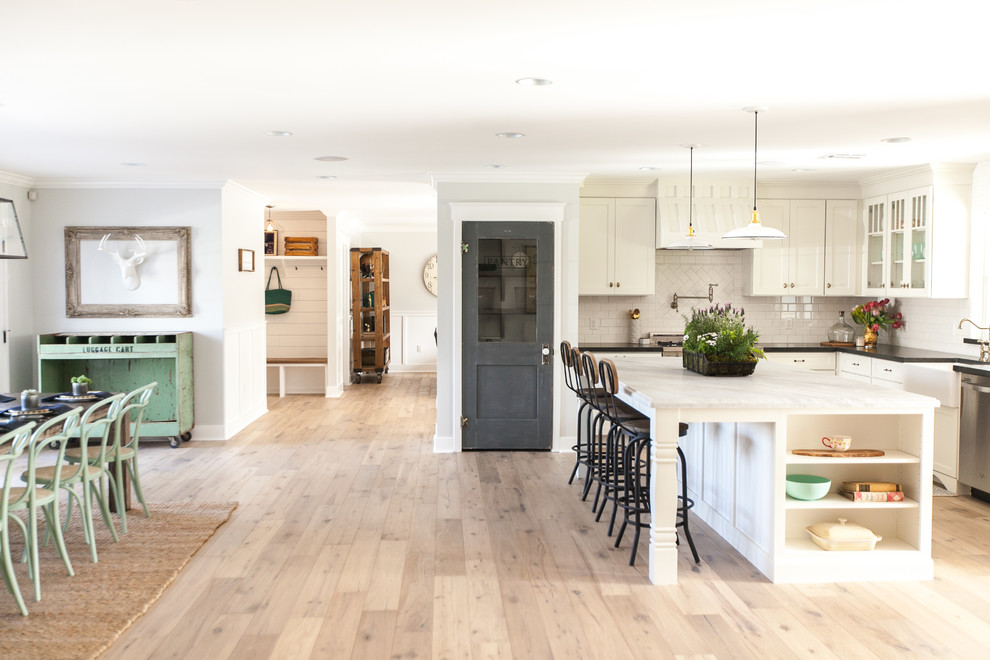 Inspiration for a large traditional l-shaped open plan kitchen in Other with a belfast sink, shaker cabinets, white cabinets, marble worktops, white splashback, metro tiled splashback, stainless steel appliances, light hardwood flooring and an island.