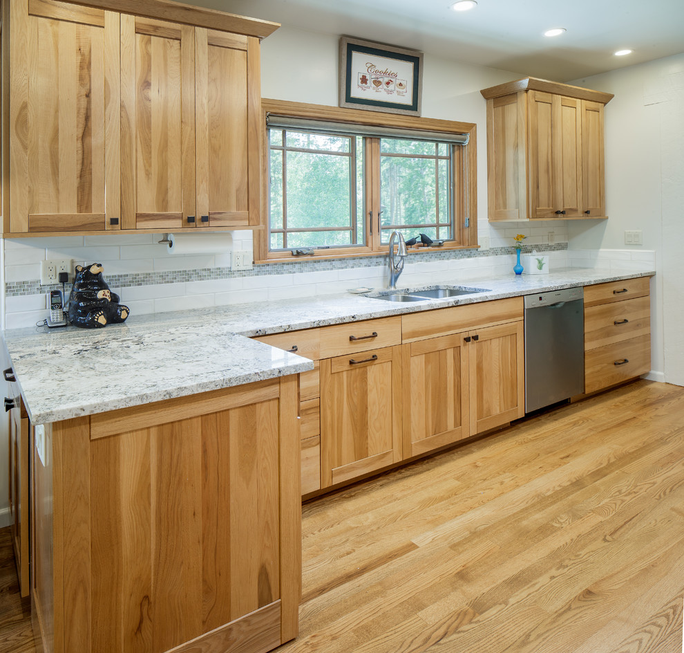 Zweizeilige Küche mit Vorratsschrank, hellen Holzschränken, Granit-Arbeitsplatte, Küchengeräten aus Edelstahl und hellem Holzboden in Denver
